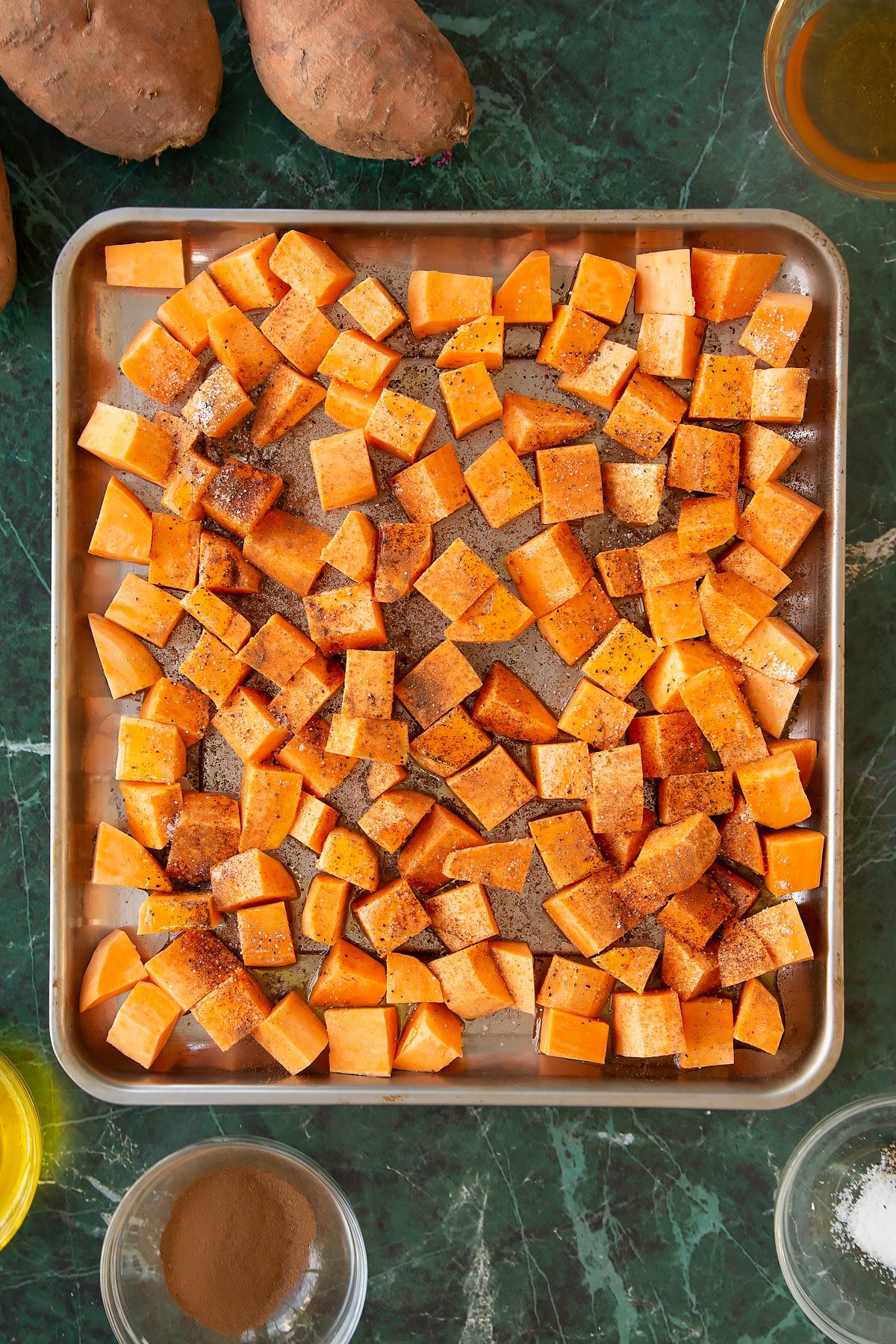 Sprinkling seasoning over the chopped sweet potatoes.