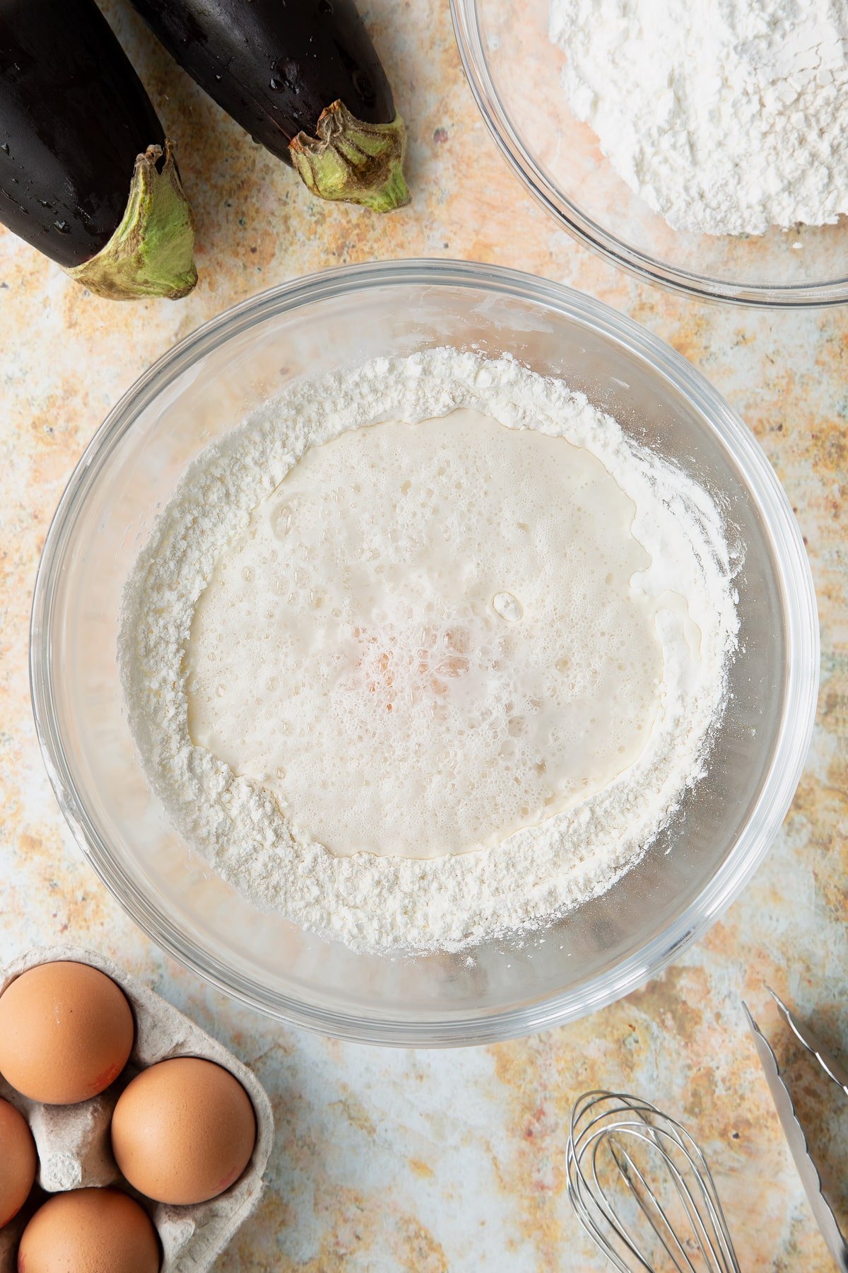 Adding the egg yolk and fizzy water to the mixing bowl of dry ingredients.