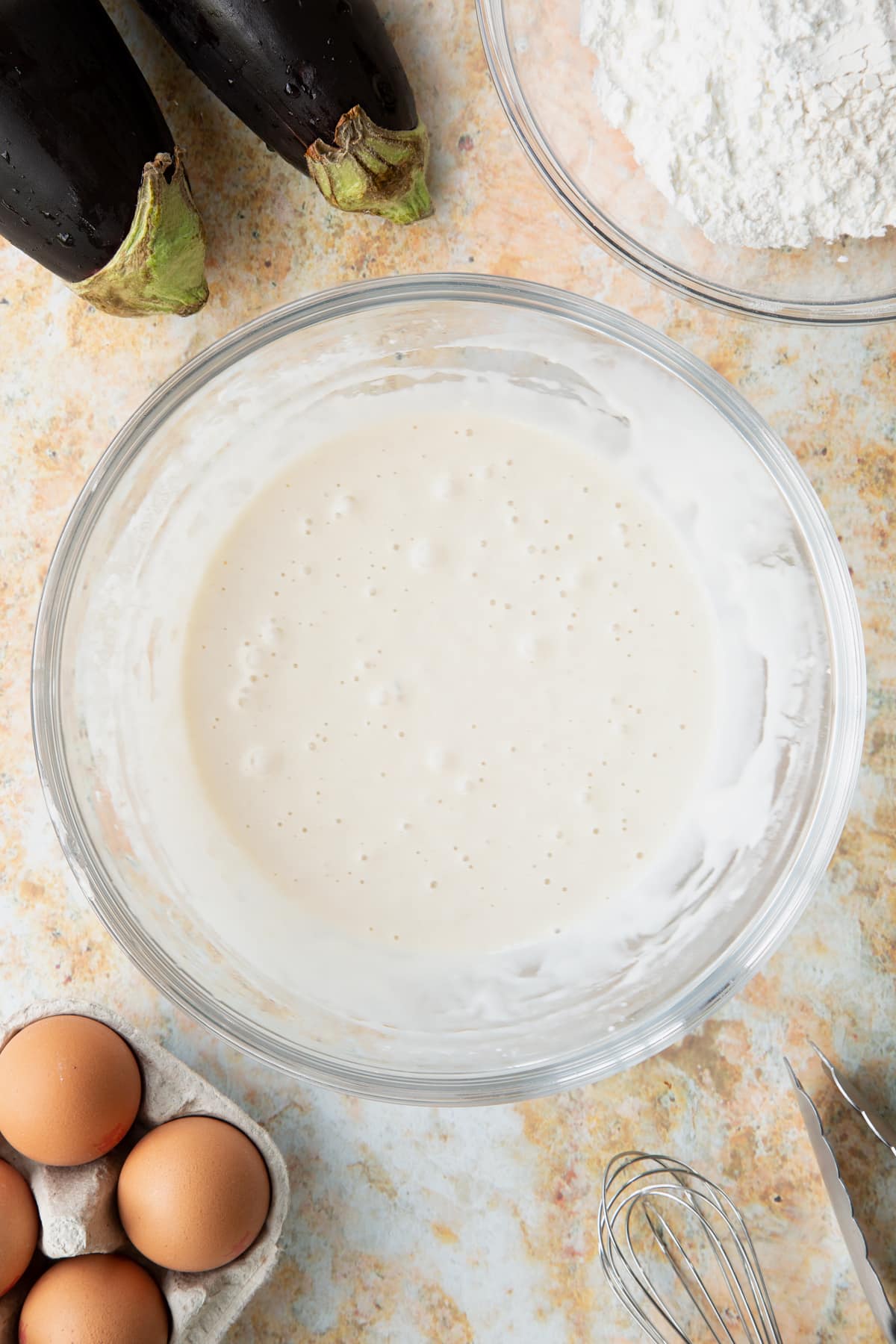 Mixing the ingredients together for the tempura batter inside a glass mixing bowl.