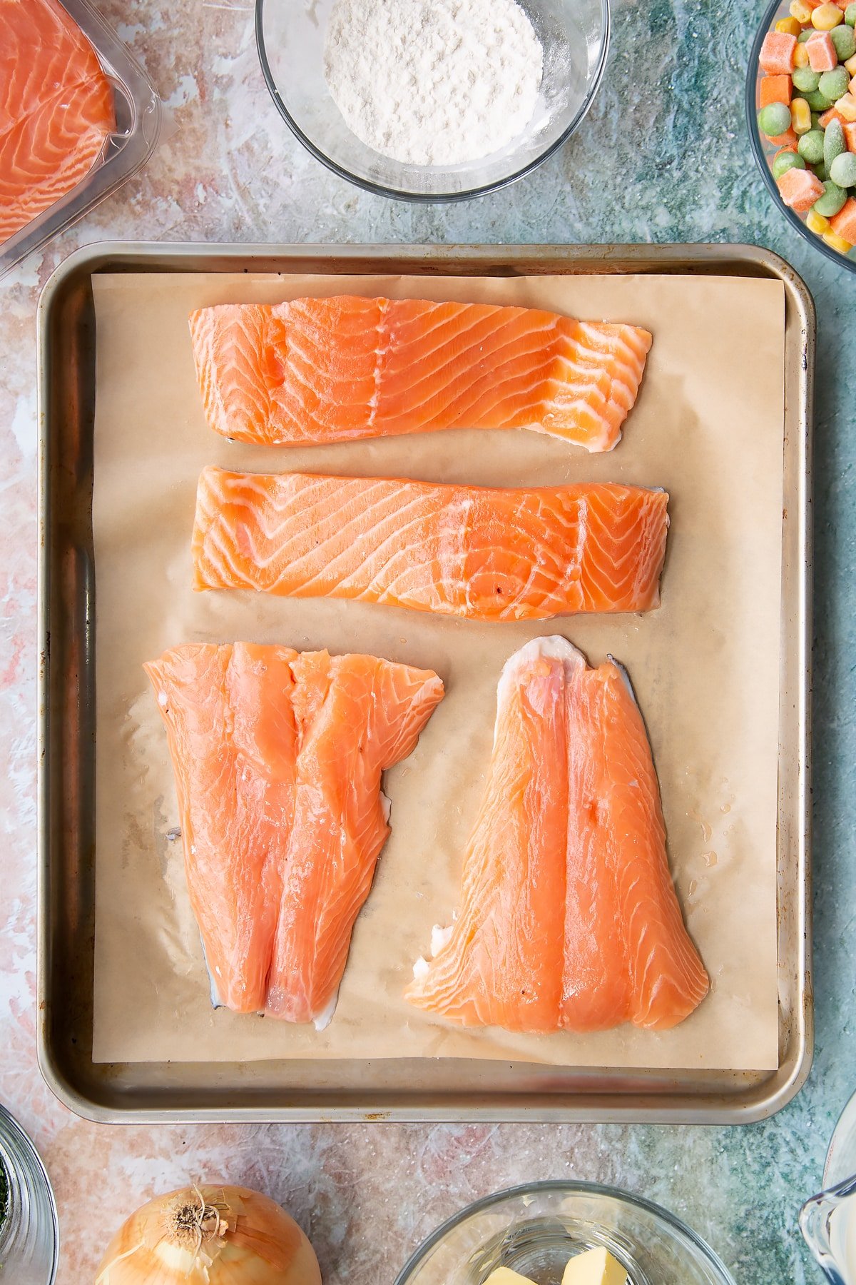 Large pieces of salmon laid out on a large baking sheet.