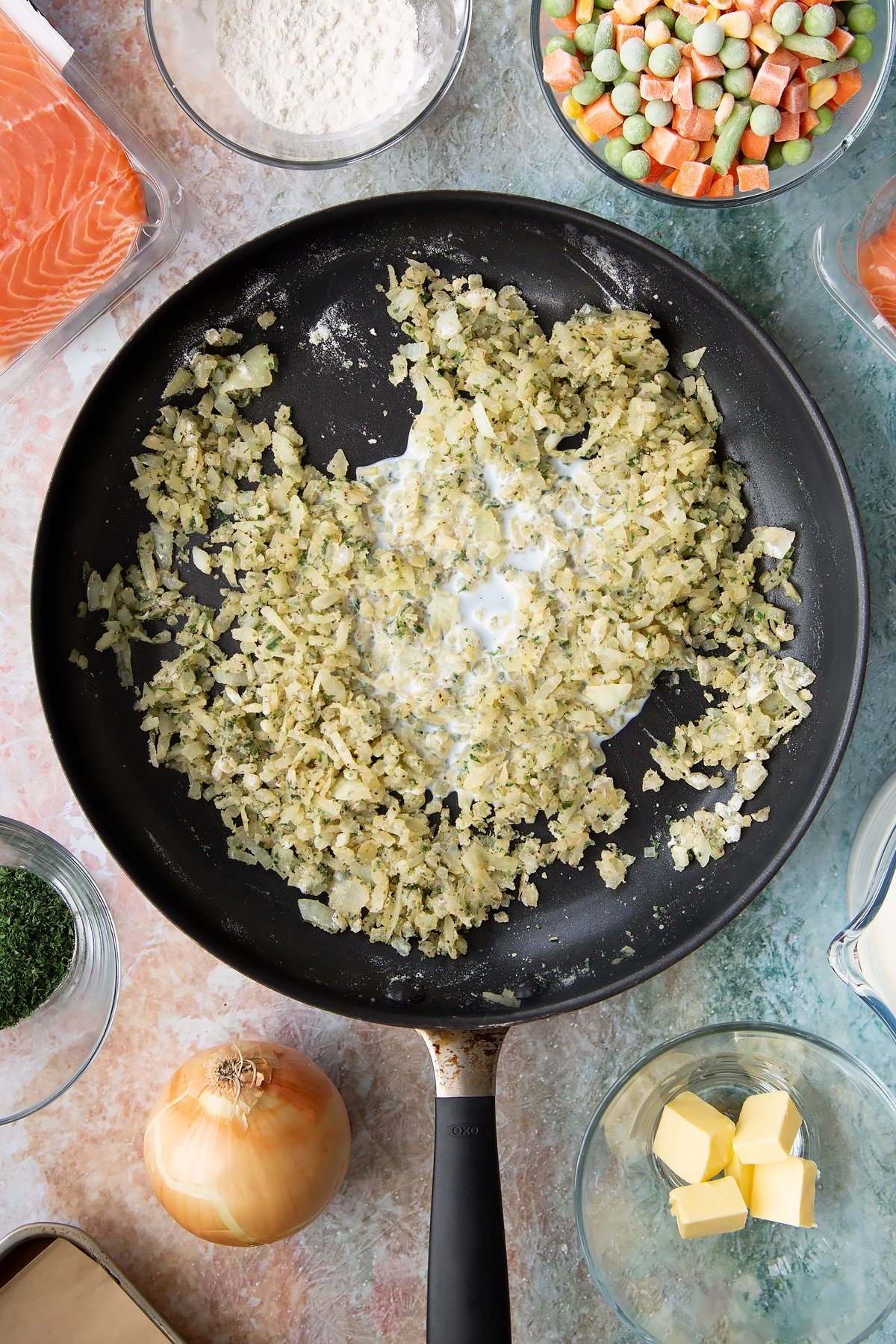 Adding a splash of milk to the pan of slicd onions.