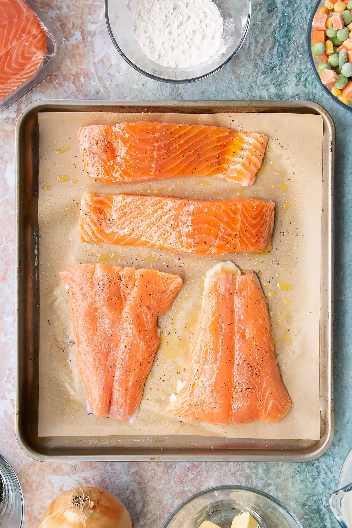 Overhead shot of the large salmon pieces on a baking tray before being moved to the oven.