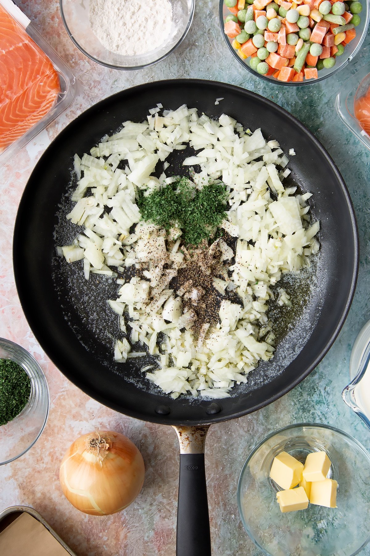 Adding sliced onions and herbs to the frying pan.